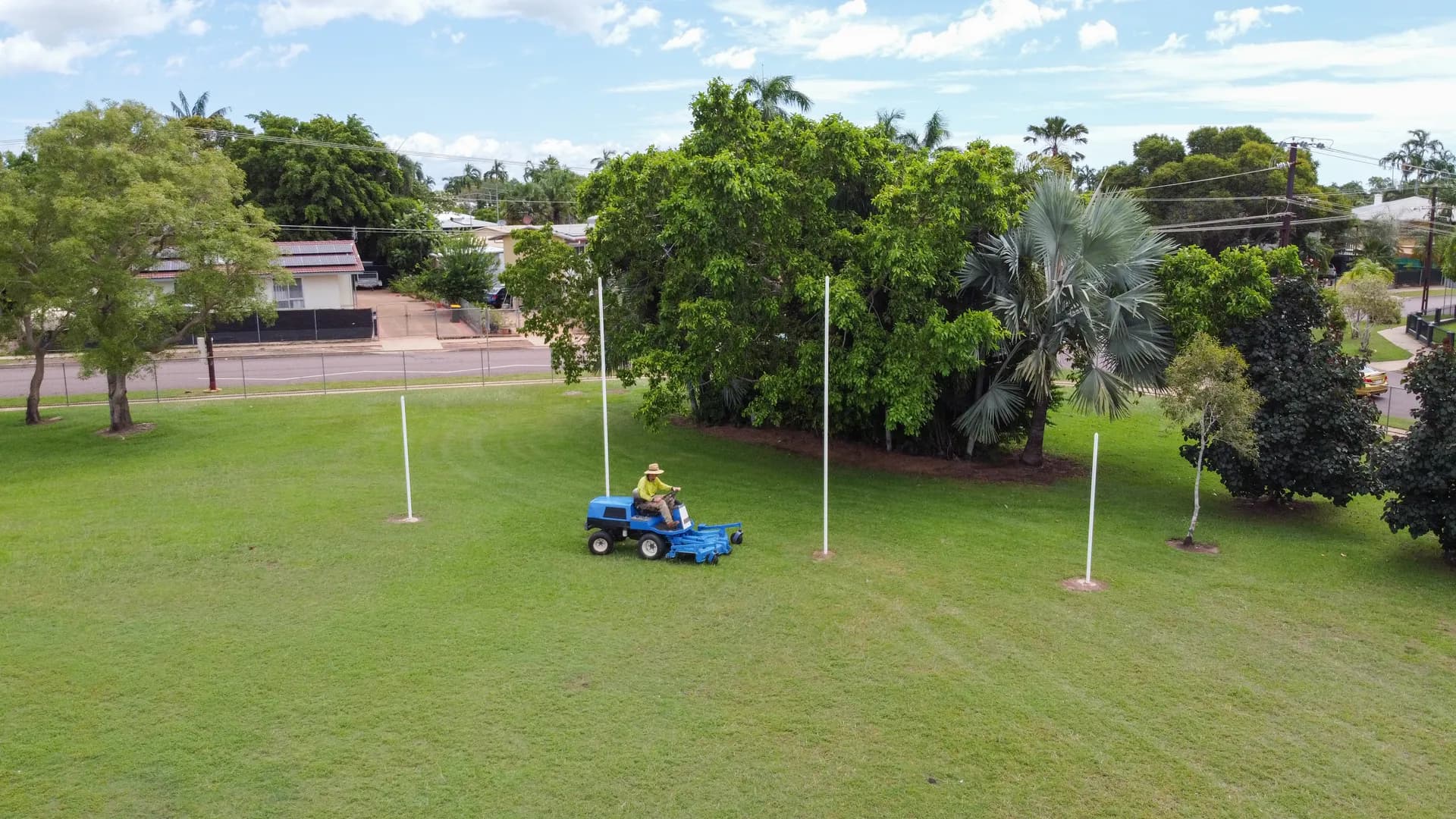 Aerial view of mower on green field with tropical trees