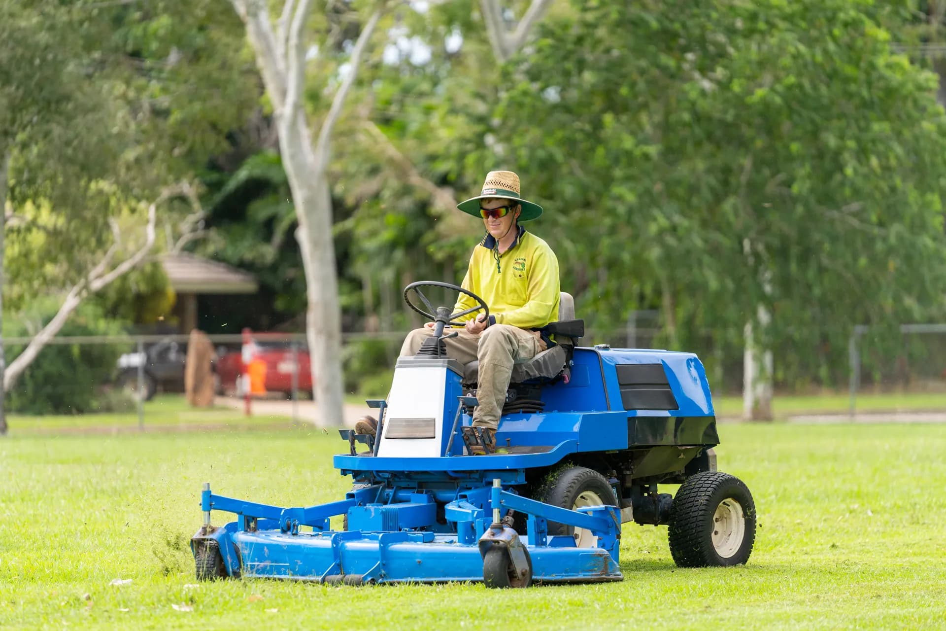 Green Ant Gardeners ride-on mower in action on a sports field