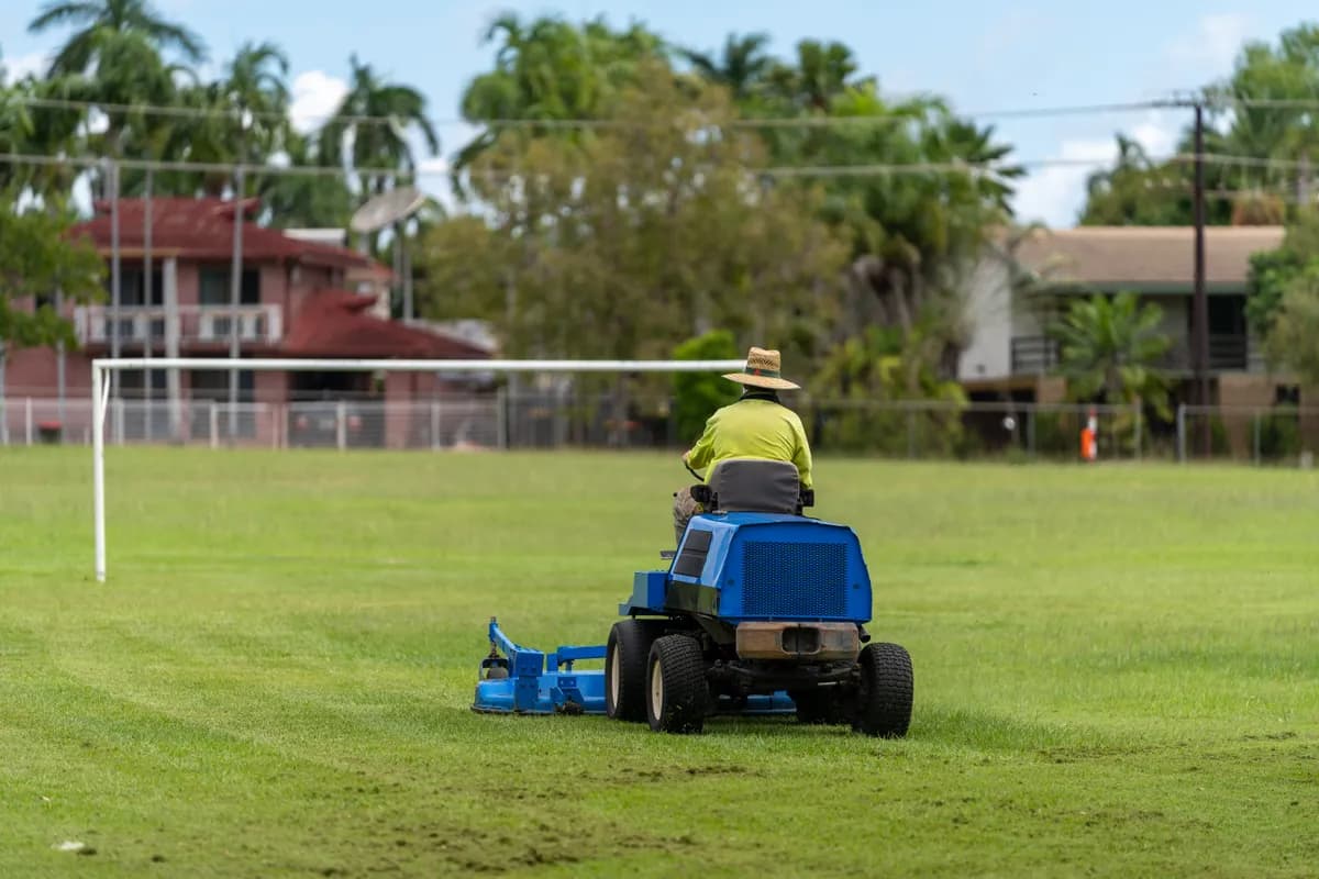 Ride-on mower approaching on a sports field